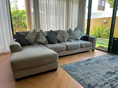 Large L-shaped grey fabric sofa with chaise and cushions
