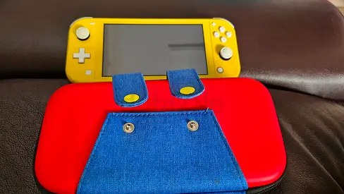 Yellow Nintendo Switch Lite with red protective case and denim pouch