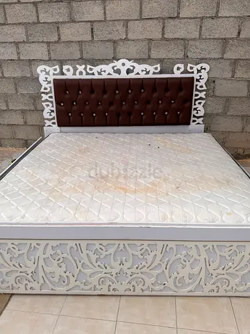 White carved wooden double bed with tufted headboard and mattress