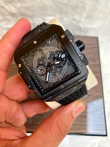 The watch pictured is a Hublot Square Bang Unico All Black (Ref. 821.CX.0140.RX), featuring a 42mm m