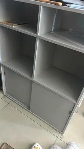 Grey freestanding storage cabinet with shelves and sliding doors