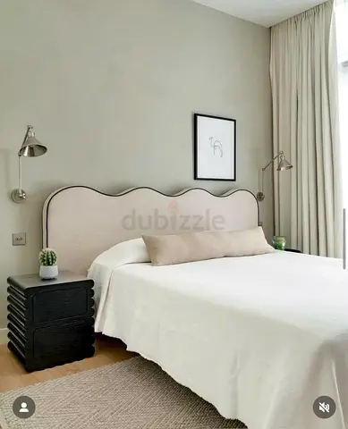 Neutral upholstered double bed with scalloped headboard
