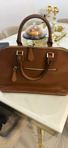 Brown leather tote handbag with top handles and zip pocket