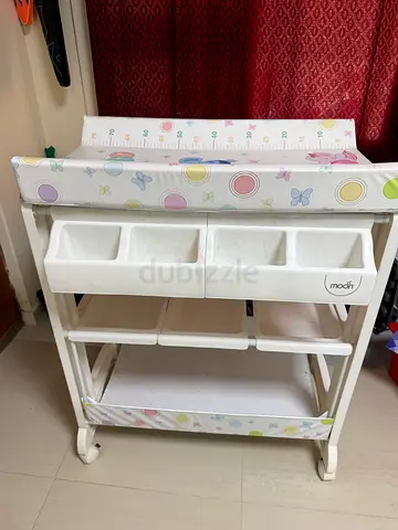 White baby changing table with storage shelves and padded mat