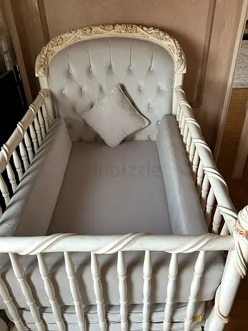 Antique-style white wooden baby crib with mattress and cushioning