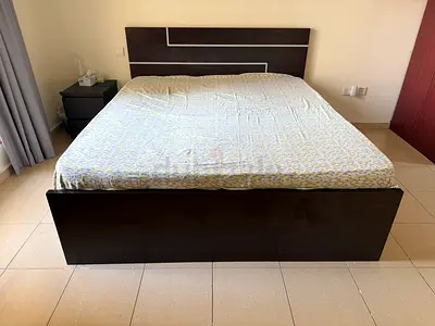 Queen-sized dark wood bed frame with headboard and mattress and side table
