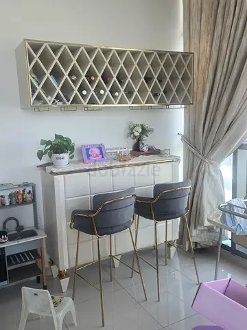 White marble-top bar counter with two grey velvet bar stools