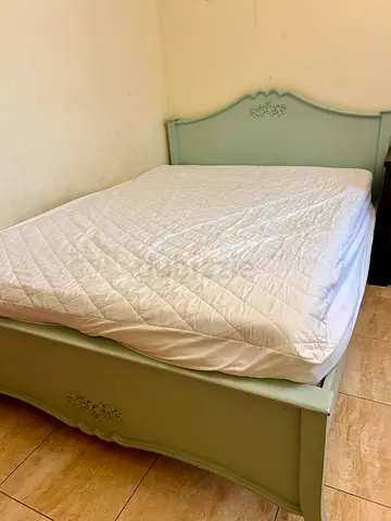 Pastel green wooden queen size bed with decorative headboard
