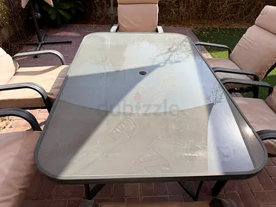 Outdoor glass-top dining table with 6 cushioned chairs