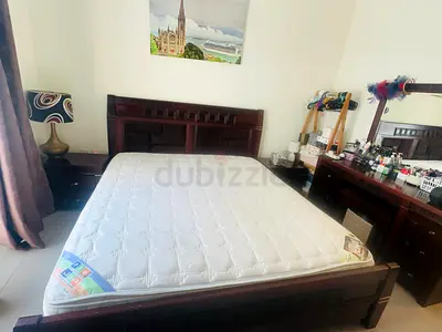 Solid dark wood double bed frame with mattress and matching bedside tables, dresser and stool