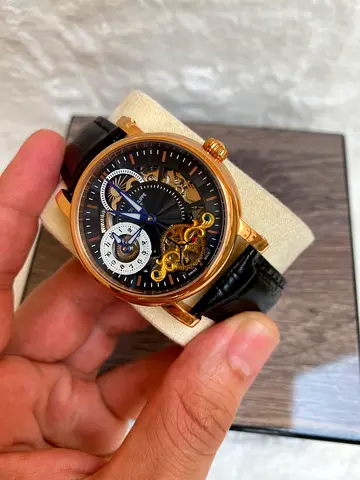 This Patek Philippe-branded skeleton watch features a rose gold-toned case, a black textured dial wi