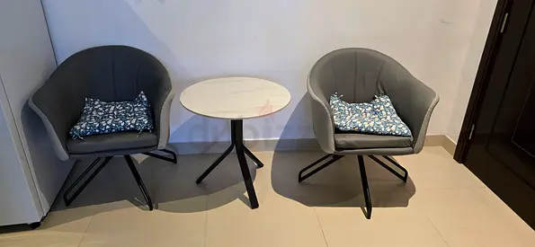 Pair of grey swivel lounge chairs with small round side table