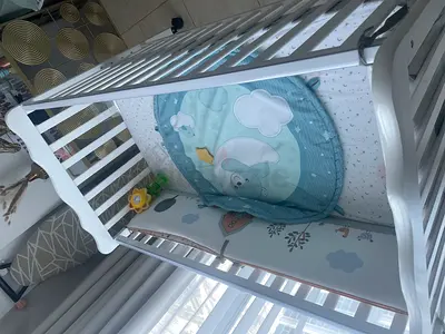 White wooden baby crib with mattress and bumper