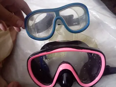 Two snorkeling/diving masks – one pink-black, one blue-clear, used
