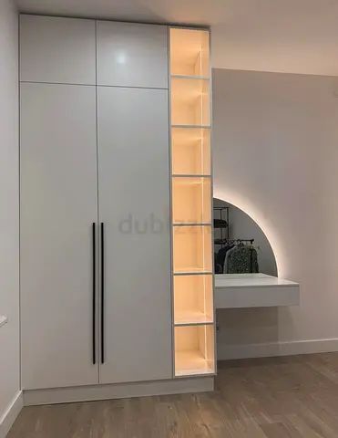 Built-in white wardrobe with illuminated open shelving and vanity alcove