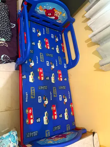 Blue Toddler Bed with Safety Rails and Car Themed cover.