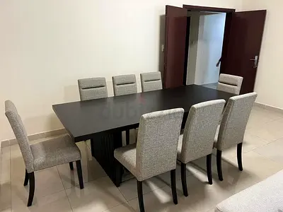 8-seater modern dark wood dining table with upholstered chairs made of solid wood.