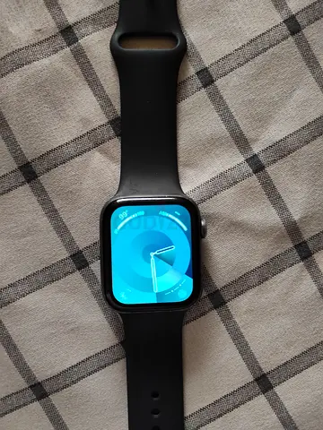 Used Apple Watch Series 4-style smartwatch with black strap and charger cable