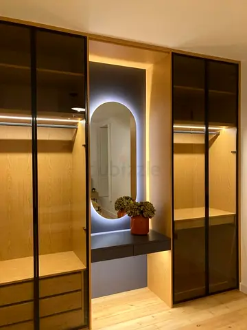 Built-in wooden wardrobe with glass doors and backlit vanity