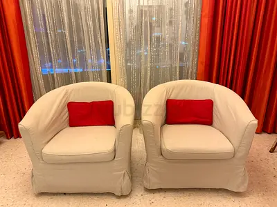 Pair of Beige Upholstered Armchairs with Red Pillows.