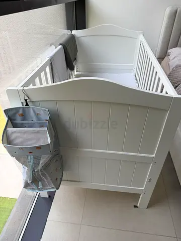 White wooden baby crib with mattress