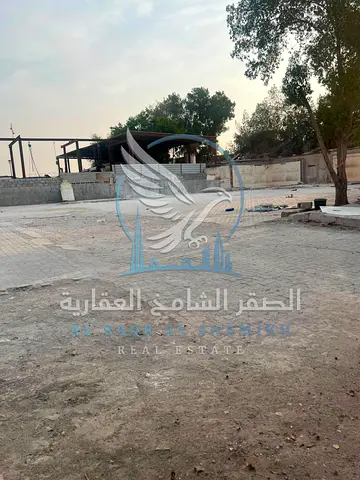 Prime yard for rent in Al Sajaa, 20,000 sq.ft, corner location, 2 offices, 3 rooms, 3 kitchens, 5 bathrooms, and 50KV power for industrial & commercia