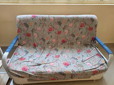 Two-seater sofa bed with floral cover  - GOOD CONDITION