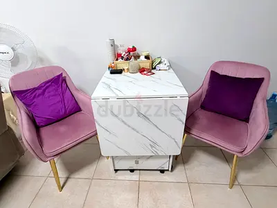 Compact marble-effect drop-leaf dining table on wheels with two pink velvet chairs