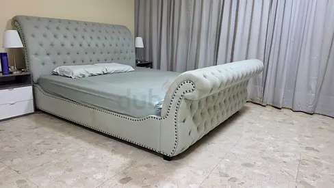 Light sage green upholstered king-size bed with tufted headboard and footboard
