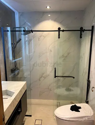 Modern frameless sliding glass shower enclosure with black hardware