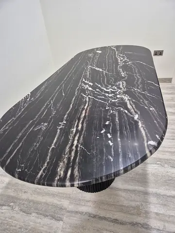 Black marble dining table with rounded edges — single pedestal base