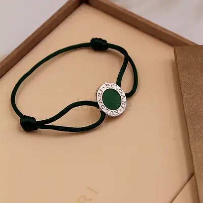 Green cord bracelet with circular metal charm
