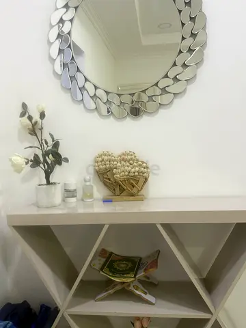 Round decorative wall mirror with white display shelving unit