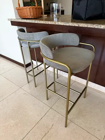 Pair of West Elm brass-frame bar stools with grey velvet upholstery.