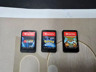 Three Nintendo Switch Game Cartridges: Mario Tennis Aces, Pokémon Diamond, Donkey Kong Country