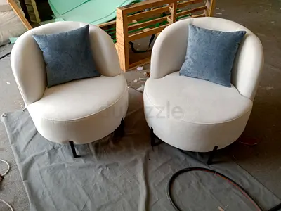 Pair of cream round accent lounge chairs with blue cushions