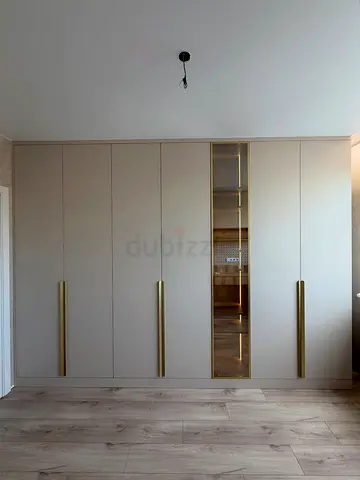 Built-in floor-to-ceiling wardrobe with mirror and brass handles