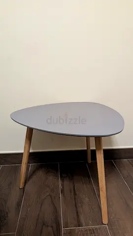 Small triangular side table with light grey top and wooden legs