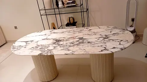 Oval marble-top dining table with fluted column bases