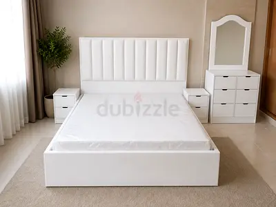 White upholstered double bed with matching bedside tables and dresser