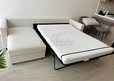 Light beige L-shaped sofa bed with pull-out bed - good condition