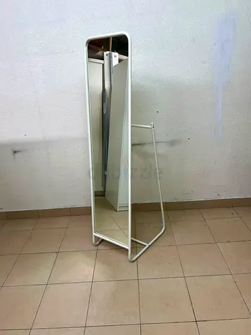 Full-length freestanding mirror with metal frame and small clothes rail