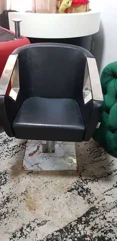 Black salon styling chair with chrome accents, adjustable base