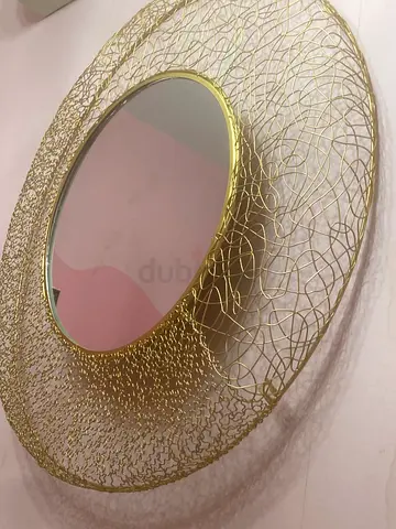 Round gold decorative wall mirror with intricate wire frame