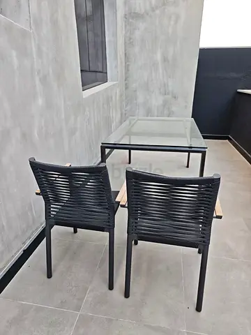 Glass-top outdoor dining table with 2 woven chairs - good condition