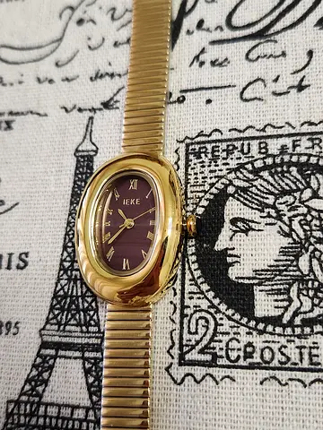 Vintage gold-tone women's wristwatch with burgundy dial