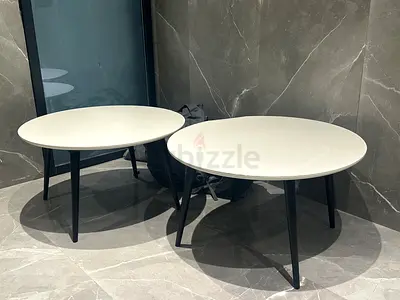 Pair of round modern coffee tables with white tops and black legs