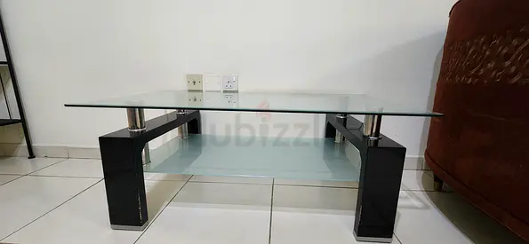 Modern glass coffee table with black legs and lower shelf