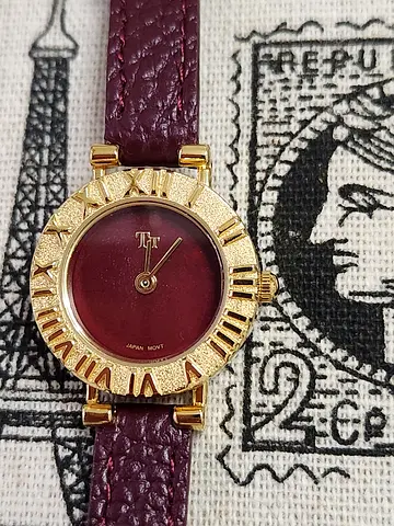 Vintage gold-tone women's wristwatch with burgundy dial and leather strap
