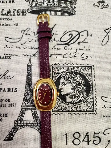 Women's vintage-style burgundy leather wristwatch with gold-tone oval case